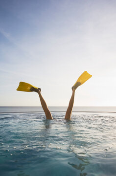 Legs of woman with flippers doing handstand in swimming pool