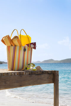 Beach bag with accessories on tropical beach