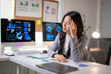 A woman is sitting at a desk with a computer monitor in front of her