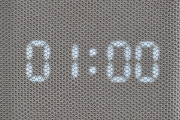 Digital timer showing 01:00 minutes displayed through mesh textile surface. Macro shot of illuminated electronic countdown digits. Technology and timekeeping concept for design and print