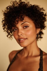 portrait of beautiful 30 years old mulatto woman with curly hair on beige background