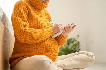 Expecting mother writing essential items list for maternity hospital in cozy home setting....