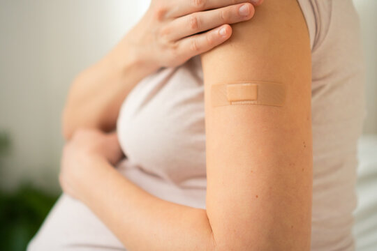 Detailed view of expecting mother's arm with fresh vaccination bandage. Important step in scheduled prenatal immunization program.