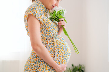 Delicate white blossoms complement expecting mother's gentle belly caress. Intimate moment of pregnancy joy and natural beauty.