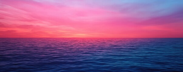 Obraz premium A vibrant pink and purple sunset over a calm ocean, with rippling water beneath a colorful sky.