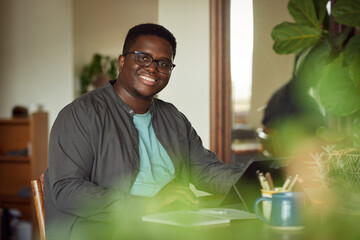 Young African man smiling while working from home on a tablet