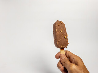 Hand holding a delicious chocolate ice cream bar with nuts on white background