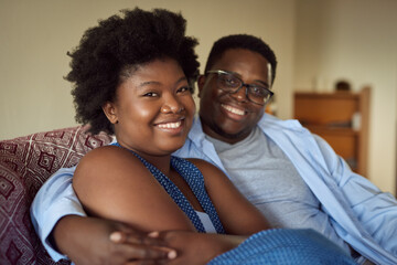 Affectionate young African couple sitting together on a living room sofa