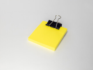 Yellow sticky notes with a black clip on a light gray background.