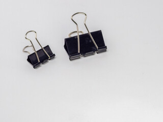 Two Black Binder Clips on a White Background with Copy Space