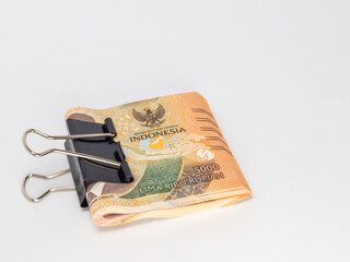 Indonesian Rupiah banknotes held together with a black binder clip