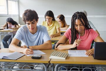 African American Girl writing essay test at college classroom - High school teenager students taking exam
