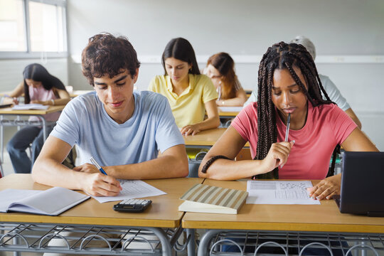 African American Girl writing essay test at college classroom - High school teenager students taking exam
