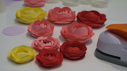 Papercraft rose flowers made paper that are arranged using a cup or glass.