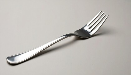 Shiny fork positioned elegantly on a soft grey background, showcasing its smooth curves and design.