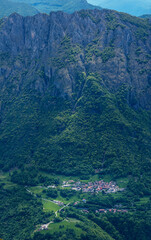 Enchanting vertical view of Parlasco village, nestled storybook-like at the foot of the Pizzi di Parlasco, bathed in magical, soft light that enhances its fairytale charm. Valsassina.