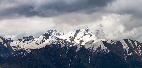 Sweeping panorama of the snow-dusted Pizzo dei Tre Signori mountain range under a vast, cloud-streaked sky, showcasing its jagged peaks and wild alpine beauty. Orobie Alps, Lombardy