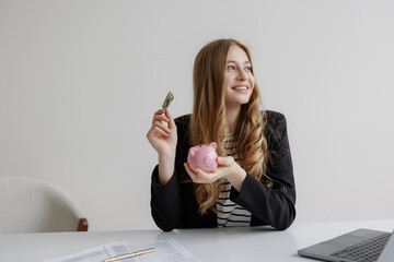 Successful woman managing savings while holding a piggy bank and cash in a modern office setting