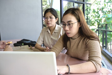 Young female collage students looking at  computer laptop studying outdoor campus