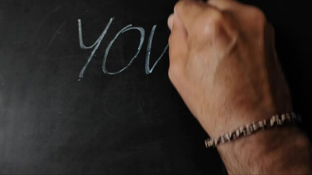 hand writing "YOU are enough" on blackboard