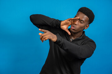 Young man pointing and covering eye on blue background