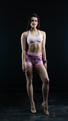 Obraz premium Confident fitness model posing on black background showing muscles 