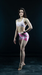 Obraz premium Confident fitness model posing on black background showing muscles 
