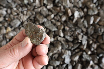 Nickel mine, mining. Hand holding piece of pentlandite ore. Rocks, textured. Used in alloys such as stainless steel, nickel-cadmium rechargeable batteries, coins