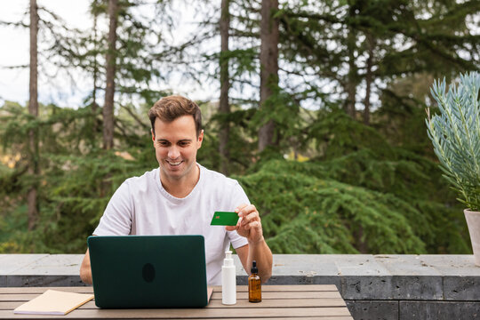 Man buying body products online using laptop and credit card outdoors