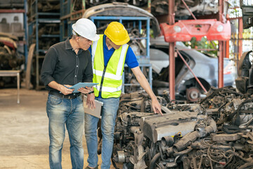 used car part business owner working check stock order with young technician man in second hand vehicle spare part center warehouse