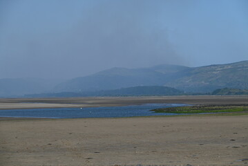 a view of the river Dovey from ynyslas beach with the smoke from a wild fire close to Machynlleth in the background 