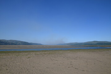 a view of the river Dovey from ynyslas beach with the smoke from a wild fire close to Machynlleth in the background 