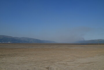 a view of the river Dovey from ynyslas beach with the smoke from a wild fire close to Machynlleth in the background 