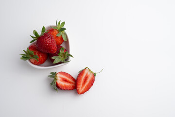 Ripe strawberries on a heart-shaped plate on a light background. Healthy food.