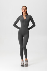 Fitness woman in jumpsuit. Athletic girl on the gray background
