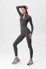 Fitness woman in jumpsuit. Athletic girl on the gray background