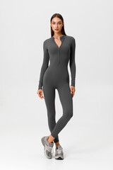 Fitness woman in jumpsuit. Athletic girl on the gray background