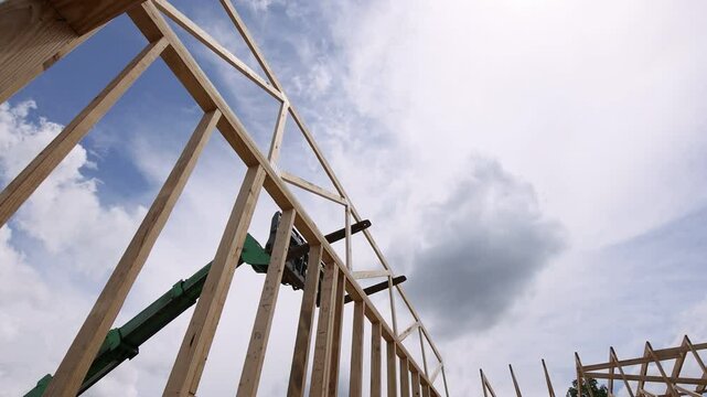 Heavy telehandler machinery lifts wooden beams for construction of new structure on construction area.