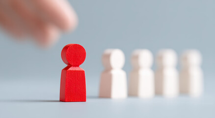 One hand selects a red wooden figure, symbolizing talent selection
