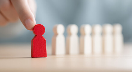 One hand selects a red wooden figure, symbolizing talent selection