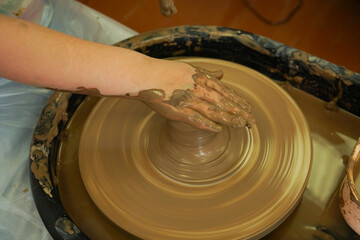 The potter's wheel. A close-up of the hands of a craftsman skillfully working with clay on a potter's wheel, giving it the shape of a clay product