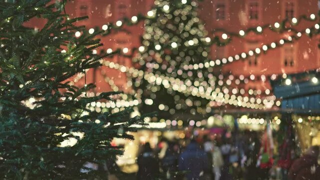 People stroll through the market square with decorated tree at Christmas market. Holiday market ambiance fills the air with festive lights and cheerful gatherings, first snow falling