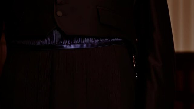 Close up of a tuxedo vest with cummerbund and dark pleated formal trousers, a traditional dress code.