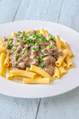 Beef stroganoff with rigatoni pasta, topped with fresh green onion garnish