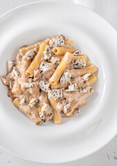 Penne pasta served with creamy walnut blue cheese sauce on white plate