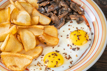 Golden potato dippers, fried eggs, and mushrooms on rustic textured table setting
