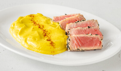 Sesame-crusted sliced tuna with cauliflower curry puree on modern white plate