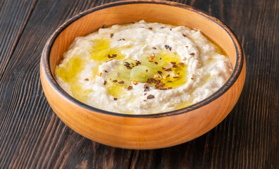 Creamy baba ghanoush in wooden bowl with chili and olive oil