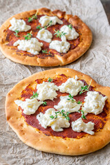 Mini pizzas baked with tomato sauce, stracciatella cheese, and fresh thyme garnish