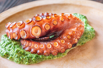 Baked Octopus Tentacles With Creamed Spinach Served On A Rustic Plate